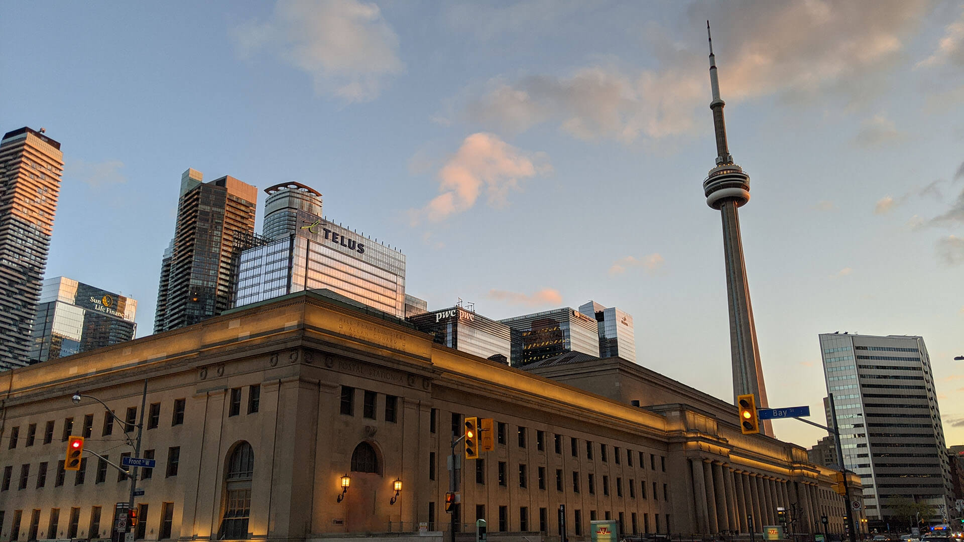A photo of Union Station, the pwc building and the CN Tower with the Bay St. street sign